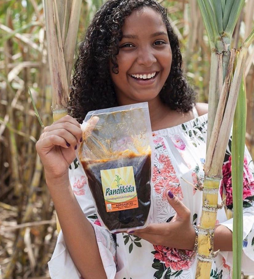 Foto de negocio verde. Mujer sonriente muestra producto panela líquida